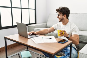 Canvas Print - Young hispanic man using laptop and drinking coffee at home