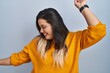 © Krakenimages.com - Young hispanic woman standing over isolated background dancing happy and cheerful, smiling moving casual and confident listening to music