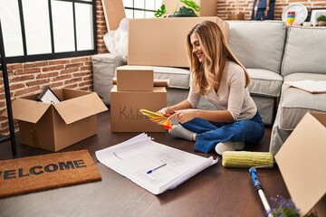 Canvas Print - Young blonde woman sittng on the floor choosing paint color at new home