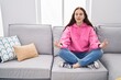 © Krakenimages.com - Young woman doing yoga exercise sitting on sofa at home