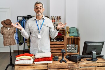 Poster - Middle age hispanic man working as manager at retail boutique relaxed and smiling with eyes closed doing meditation gesture with fingers. yoga concept.