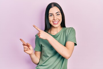 Wall Mural - Beautiful woman with blue eyes wearing casual t shirt smiling and looking at the camera pointing with two hands and fingers to the side.