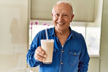 Poster - Senior man smiling confident holding glass of smoothie at kitchen