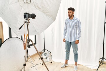 Poster - Arab young man posing as model at photography studio in shock face, looking skeptical and sarcastic, surprised with open mouth