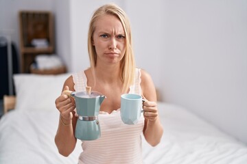 Poster - Young caucasian woman drinking coffee on the bed skeptic and nervous, frowning upset because of problem. negative person.