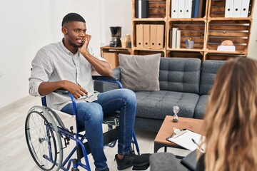 Sticker - African american man doing therapy sitting on wheelchair looking stressed and nervous with hands on mouth biting nails. anxiety problem.