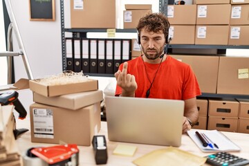 Sticker - Young hispanic call center agent man working at warehouse showing middle finger, impolite and rude fuck off expression