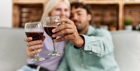 Poster - Young couple smiling happy toasting with red wine glass at home.