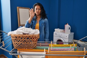 Sticker - Young asian woman hanging clothes at clothesline doing stop sing with palm of the hand. warning expression with negative and serious gesture on the face.