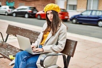 Wall Mural - Young hispanic girl with serious expression working using laptop at the city.