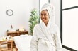 © Krakenimages.com - Young brunette woman wearing towel and bathrobe standing at beauty center looking away to side with smile on face, natural expression. laughing confident.