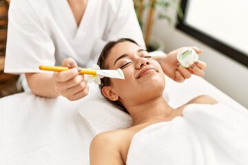 Poster - Young latin woman relaxed having skin face aloe vera treatment at beauty center