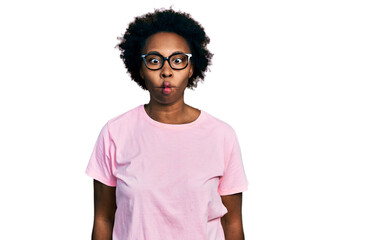 African american woman with afro hair wearing casual clothes and glasses making fish face with lips, crazy and comical gesture. funny expression.