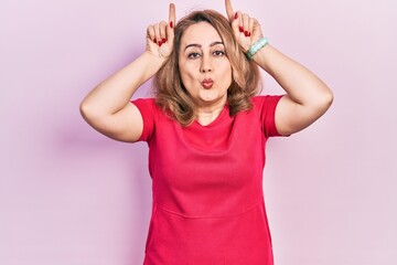 Poster - Middle age caucasian woman wearing casual clothes doing funny gesture with finger over head as bull horns