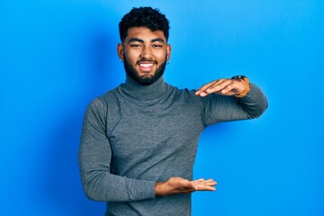 Sticker - Arab man with beard wearing turtleneck sweater gesturing with hands showing big and large size sign, measure symbol. smiling looking at the camera. measuring concept.