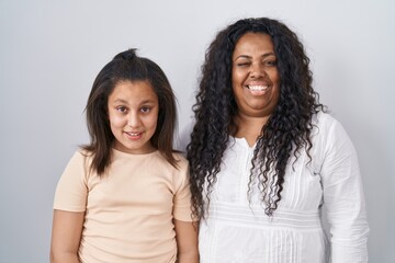 Poster - Mother and young daughter standing over white background winking looking at the camera with sexy expression, cheerful and happy face.