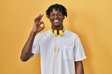 Sticker - Young african man with dreadlocks standing over yellow background smiling positive doing ok sign with hand and fingers. successful expression.