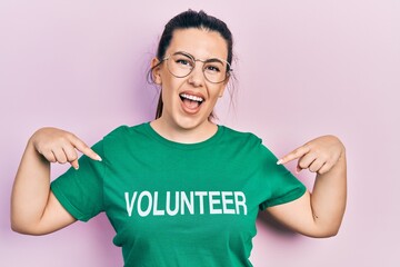 Wall Mural - Young hispanic woman wearing volunteer t shirt looking confident with smile on face, pointing oneself with fingers proud and happy.