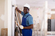 © JackF - African american contractor doing repairs in a new building plasters the wall indoors