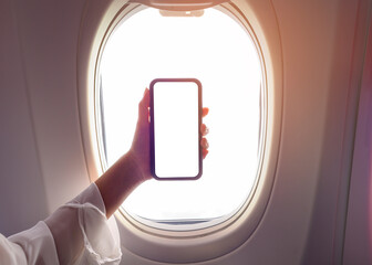Close up woman hand holding smartphone over window aircraft background , transportation technology concept