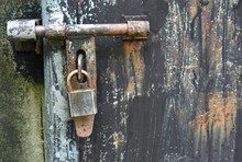Old Padlock Hanging On Rusty Metal Door 