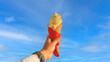 Man hand holding delicious ice cream with macadamia nuts and vanilla waffle cone with blue sky background