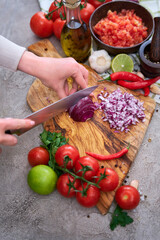 woman cutting and chopping onion by knife on wooden board