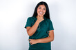 © Roquillo - Doctor hispanic woman wearing surgeon uniform over white wall looking confident at the camera smiling with crossed arms and hand raised on chin. Thinking positive.