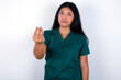 © Roquillo - Doctor hispanic woman wearing surgeon uniform over white wall Doing Italian gesture with hand and fingers confident expression