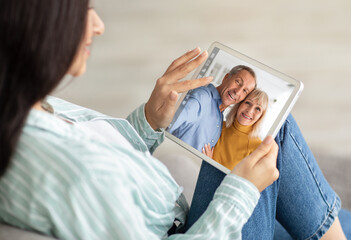 Poster - Young Woman Holding Digital Tablet And Making Video Call To Senior Parents