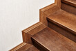 Wooden steps of indoor staircase with stair skirtboard made of toned solid oak and oak veneer close view