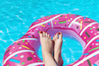 Female with perfect red pedicure over a pool. Vacation pericure. Female with bare feet over blue swimming pool water.