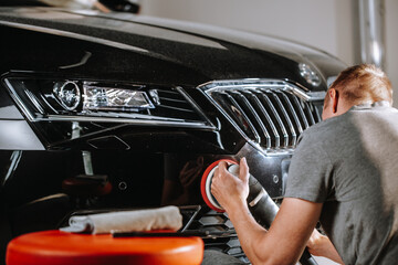 Car details concept - hands with orbital polisher in a car studio, detailing