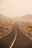 Fototapeta Do przedpokoju - road going through the plateau during a sandstorm in Sahara Desert, Morocco Africa
