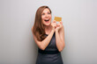 Happy business woman in gray dress with credit card looking side away. isolated female business person portrait with mouth open and positive emotion.