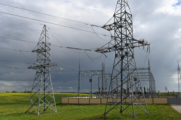 View of the power station and transmission pylons on a cloudy day. High voltage electric pole and transmission lines.