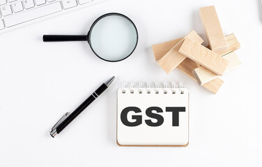 Poster - GST word written on notebook with block magnifier and pen , business concept.