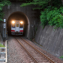 トンネルからヘッドライトを照らして現れる列車