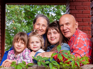 Poster - Portrait of elderly grandparents with three granddaughters on  porch of  village house.