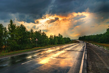 Humidity Asphalt Road Panorama In Countryside On Rainy Evening Of Summer Day. Autumn Rain Road In Forest Under Dramatic Cloudy Sunset Background