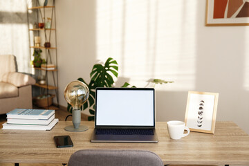 Wall Mural - Blank screen laptop, cell phone and a cup on wooden table. Cozy lofty office with house plants full of natural sunlight. Close up, copy space, background.