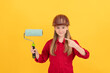 © Olena - happy teen child in builder hard hat with paint roller on yellow wall. pointing finger