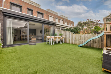 Neat paved patio with sitting area and small garden near wooden fence