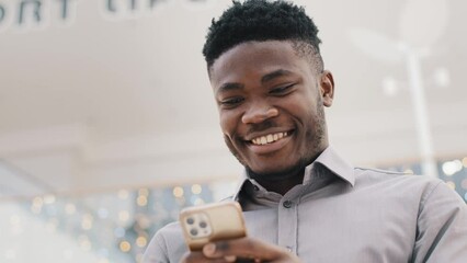 Close-up young happy man looking at phone screen smiling enjoying distance communication reads pleasant e-mail chatting with friends on social network using smartphone checks web page browsing media