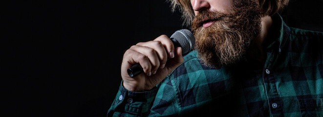 Wall Mural - Bearded man in karaoke sings a song into a microphone. Male attends karaoke. Man with a beard holding a microphone and singing