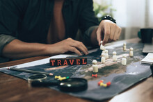Wood Box With Word " Travel" On World Map And Travelers Planning Use Small Wood Doll To Marking On Map And Finger Pointing On Map, Or Find Travel Routes. Travel Concept.