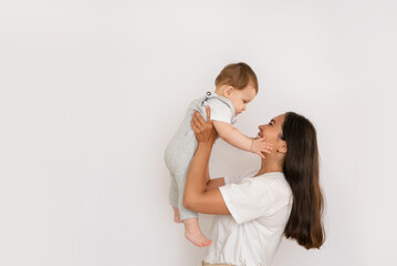 Wall Mural - Happy young mother with her baby, little son in love on white background copy space. The concept of a happy family, motherhood. mother and child portrait