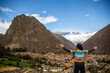 Woman looking at Ollantaytambo in the Sacred Valley in Cusco, Peru, from above on cloudy day