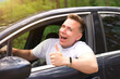 © Евгений Шемякин - portrait of nice cheerful guy, driver, young positive man, driving his car, smiling show thumb up, like gesture from automobile window. Happy buyer, customer of a new car enjoying driving. Good buy