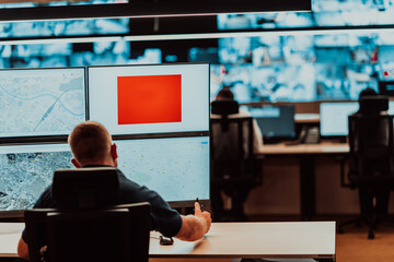 Wall Mural - Male security operator working in a data system control room offices Technical Operator Working at workstation with multiple displays, security guard working on multiple monitors Male computer opera